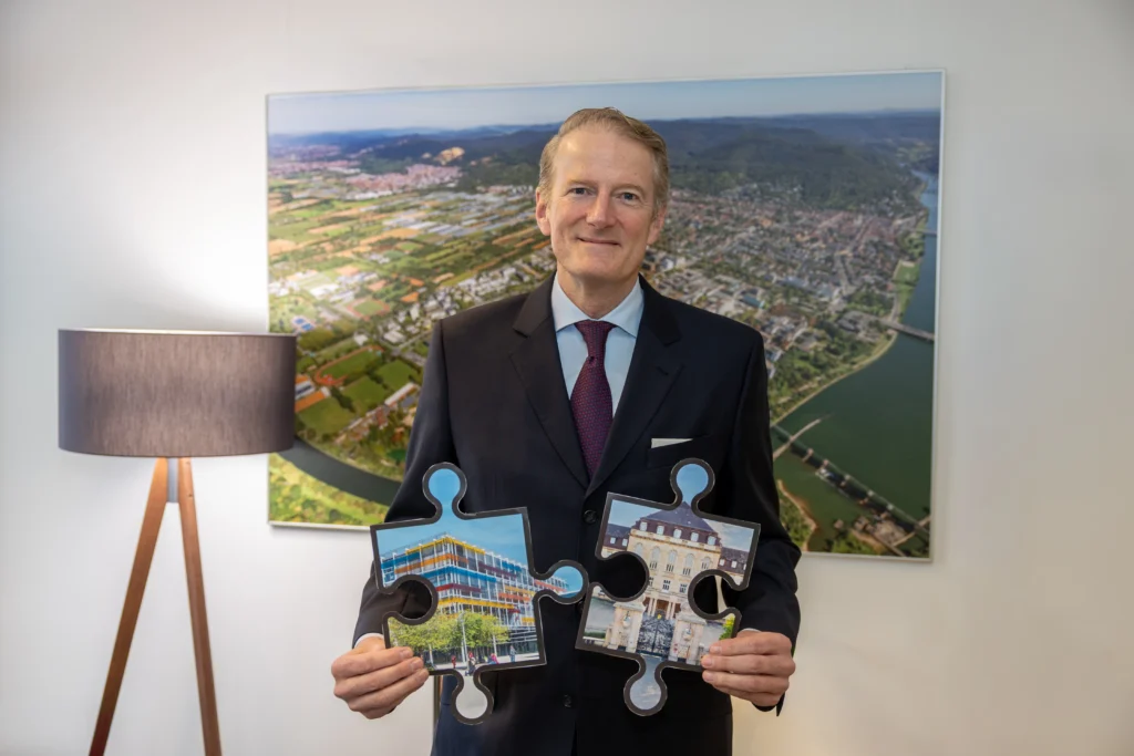Professor Dr. Hanns-Peter Knaebel fügt die Puzzleteile, die symbolisch für die Unikliniken in Heidelberg und Mannheim stehen, im Verbundsmodell zusammen. Bild: Cheesy Photo