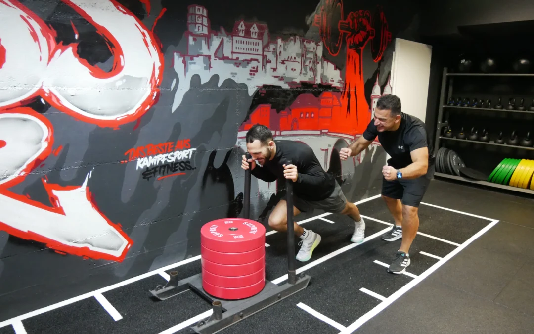 Lennart Sass gibt beim Training für das gemeinsame Hyrox-Event am Gewichtsschlitten alles – und erhält dabei von Reza Mehman moralischen Support. Bild: Benjamin Jungbluth